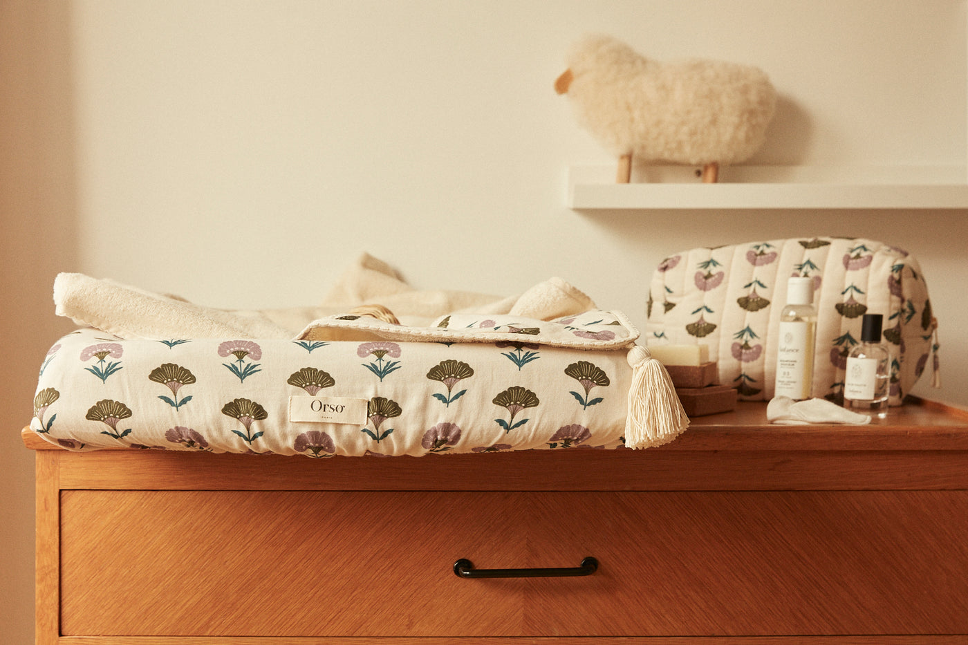 Housse de matelas à langer avec motif floral, posée sur une commode en bois