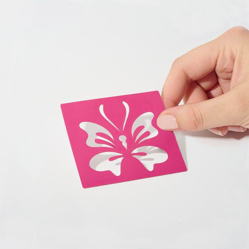 Pochoir Papillon rose tenu par une main, idéal pour décoration et artisanat