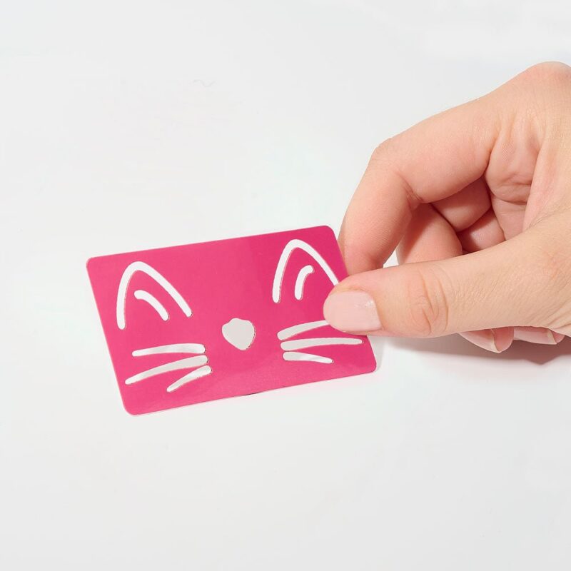 Pochoir Chat rose avec motifs de visage de chat, tenu par une main.