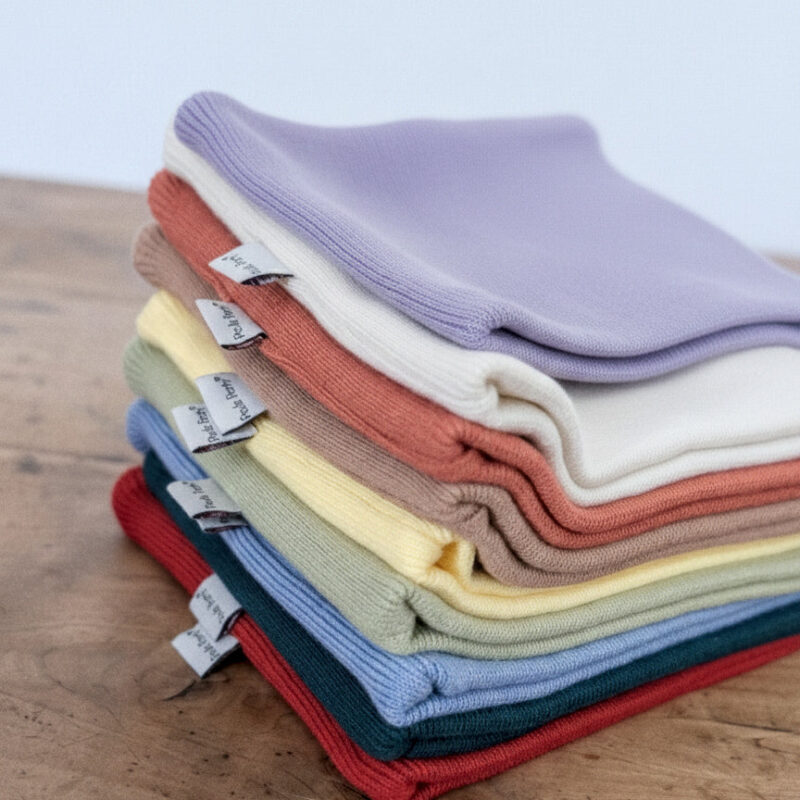 Snood Rouge Poule Party : pile de snoods colorés en tissu doux sur une table