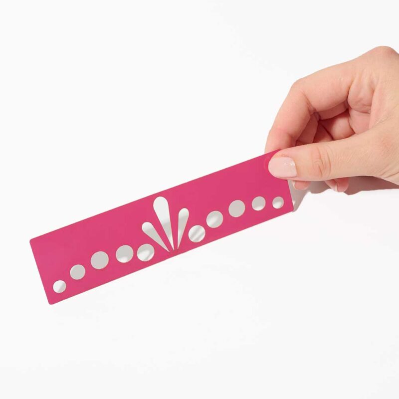 Pochoir Diadème rose tenu en main, avec motifs circulaires et floraux.