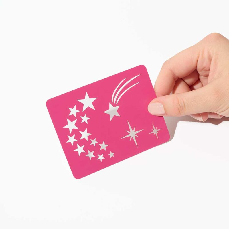 Pochoir Étoiles : main tenant un pochoir rose avec motifs d'étoiles et comète